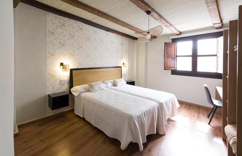 a bedroom with a white bed and a window at Hotel Juancaballo in Úbeda