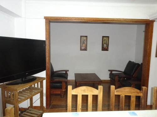 sala de estar con TV, mesa y sillas en Veranogesell en Villa Gesell