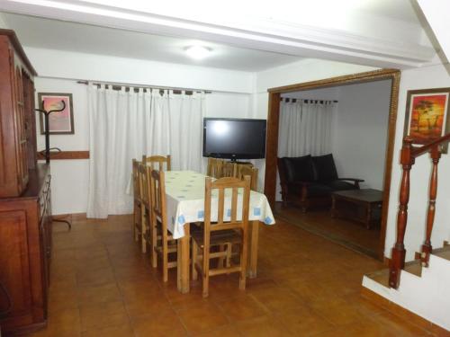 un comedor con mesa y sillas y televisión en el Veranogesell de Villa Gesell