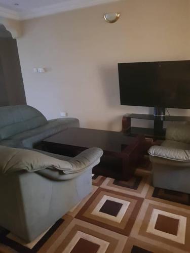 salon z kanapą i telewizorem z płaskim ekranem w obiekcie Touray Guest House w mieście Old Yundum