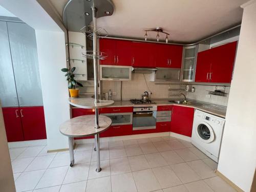 eine Küche mit roten Schränken und einem Tisch darin in der Unterkunft Fabulous apartment in Chișinău in Chişinău