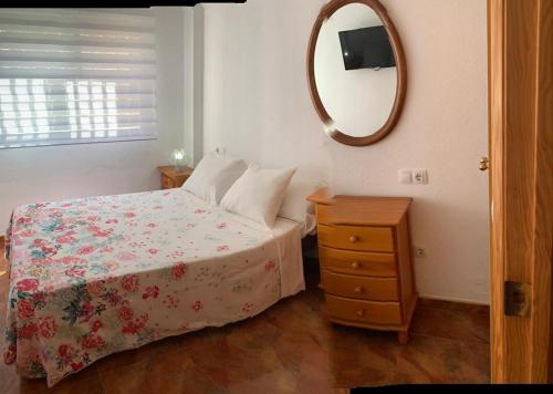 a bedroom with a bed with a dresser and a mirror at Apartamento en la playa in Tavernes de Valldigna