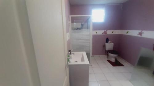 een paarse badkamer met een toilet en een wastafel bij Bel'lune in La Trinité