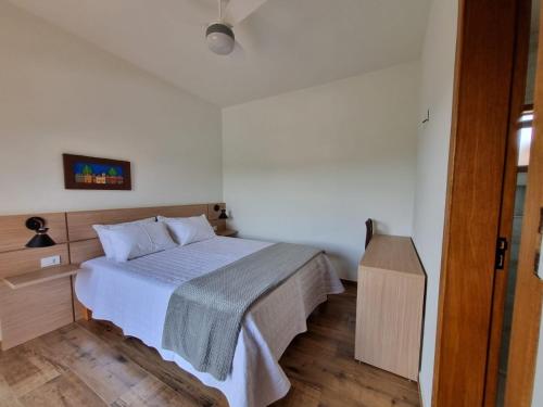 a bedroom with a bed and a wooden floor at Chalé das Palmeiras in Carrancas