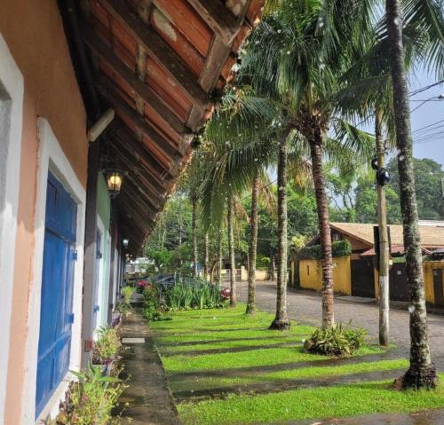 a yard with palm trees next to a building at Chales Arco-iris 2 - Para quem procura simplicidade em uma ótima localização in Ilhabela