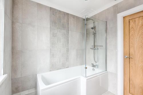 a bathroom with a shower and a white bath tub at 3-bed in Mumbles with free parking & sea views in The Mumbles