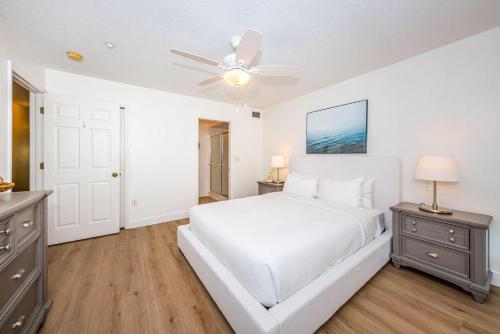 a white bedroom with a bed and a ceiling fan at White Dunes Condo in Clearwater Beach