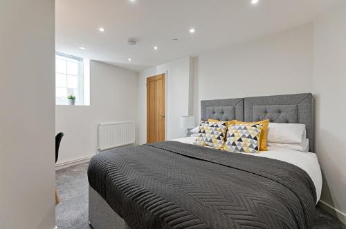 1 dormitorio con 1 cama grande con almohadas amarillas en 2 bedroom flat in The Mumbles with free parking, en Mumbles