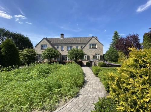 a large house with a brick walkway leading to it at Sfeervol familielandhuis in de groene Kempen in Baarle-Hertog