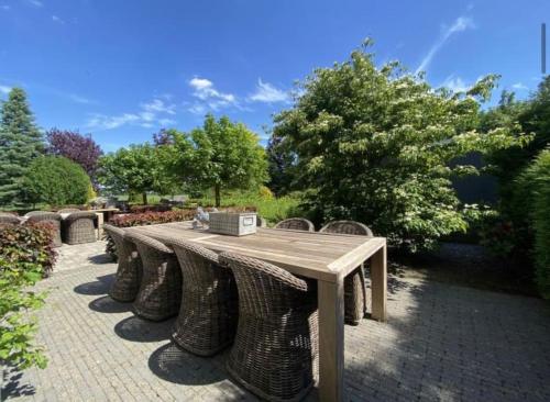 a wooden table with wicker chairs in a garden at Sfeervol familielandhuis in de groene Kempen in Baarle-Hertog
