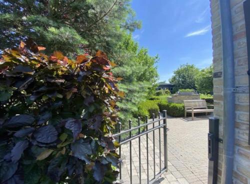 a fence in front of a park with a bench at Sfeervol familielandhuis in de groene Kempen in Baarle-Hertog