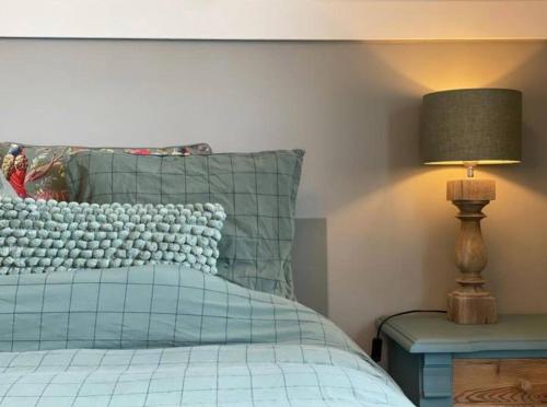 a bedroom with a bed with a lamp on a table at Sfeervol familielandhuis in de groene Kempen in Baarle-Hertog