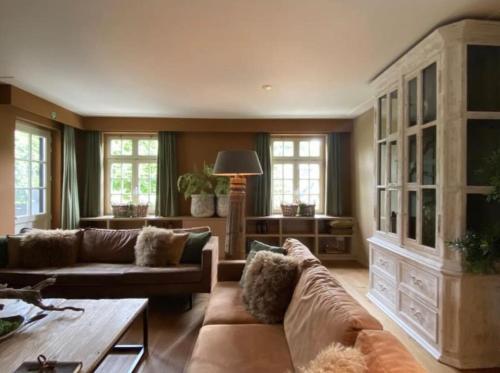 a living room with a couch and a table at Sfeervol familielandhuis in de groene Kempen in Baarle-Hertog