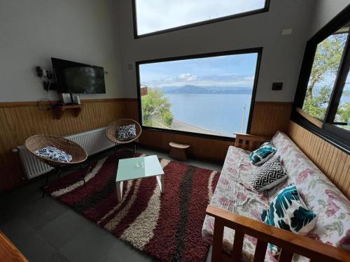 a living room with a couch and two large windows at Cabañas El Roble Lican Ray in Licán Ray