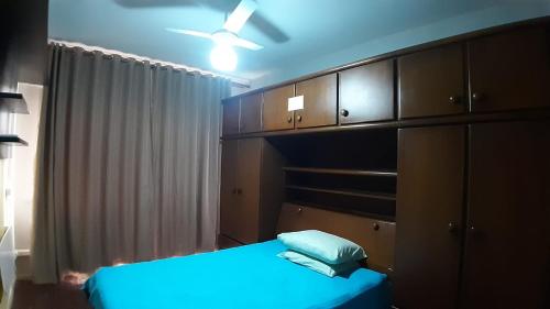 a bedroom with a blue bed and wooden cabinets at Apto acochegante com Praia e lazer in São Vicente