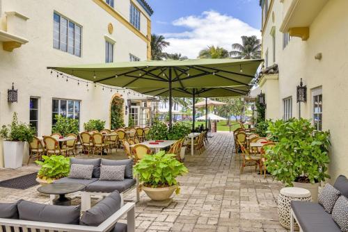 a patio with tables and chairs and a large green umbrella at Hotel Ocean in Miami Beach