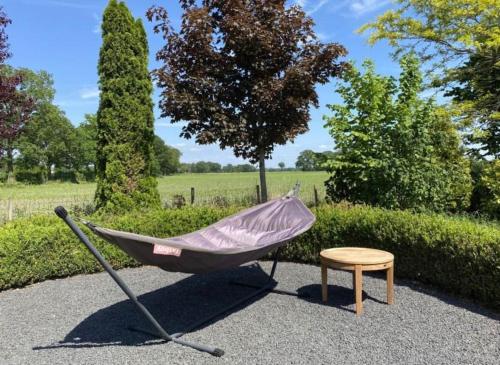 a hammock and a chair in a garden at Sfeervol familielandhuis in de groene Kempen in Baarle-Hertog