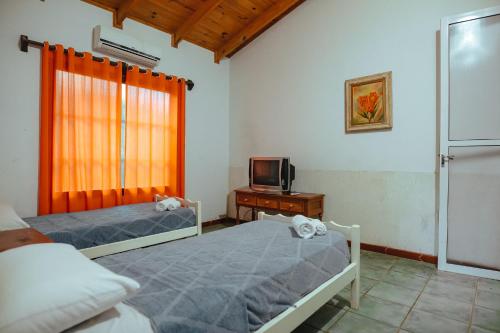 1 dormitorio con 2 camas, TV y ventana en Palo Rosa Lodge en Puerto Iguazú