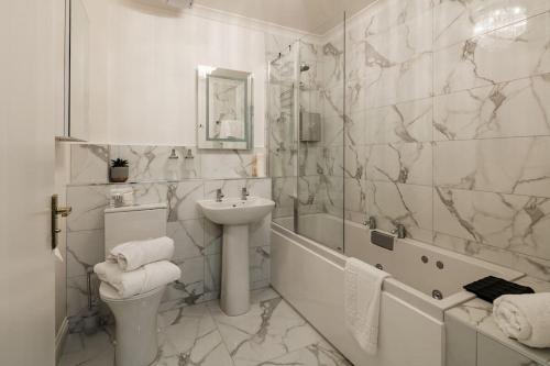 a white bathroom with a sink and a toilet at Boutique Beachside Apartment with Jacuzzi Bath, Findhorn in Findhorn