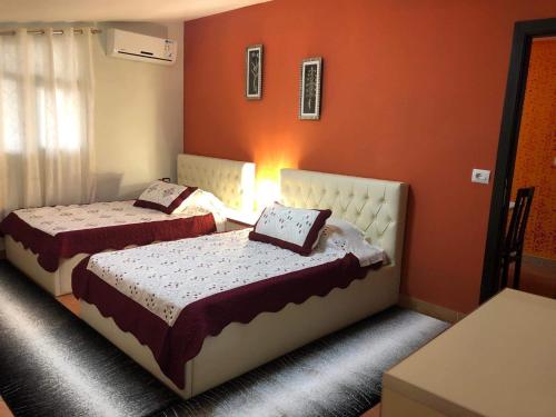 two beds in a room with orange walls at Villa Ceni in Elbasan