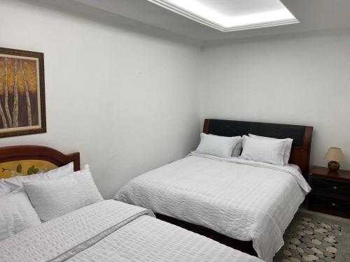 a bedroom with two beds with white sheets and a painting at El Castillo de Nallig in Gualaceo