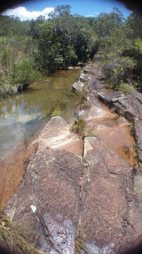 a view of a river with rocks and trees at Sitio Boa Fé - 300m das cachoeiras Moinho e Salomão in Carrancas
