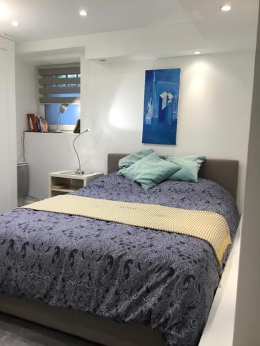 ein Schlafzimmer mit einem Bett mit einem blauen Gemälde an der Wand in der Unterkunft Studio côté Parc des Contades in Straßburg