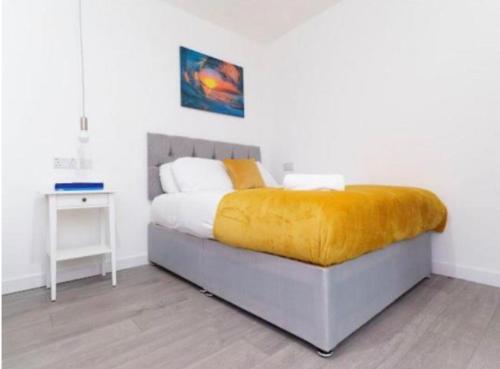 ein Schlafzimmer mit einem Bett mit einer gelben Decke darauf in der Unterkunft Bayswater Apartments with Free Parking in Leeds
