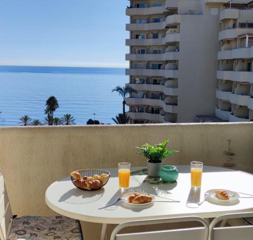 een tafel met eten en drinken op een balkon met uitzicht op de oceaan bij EL ESTUDIO DE LA PLAYA BENALBEACH Holidays Deluxe in Benalmádena