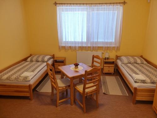 Penzión Oponice في Oponice: غرفة بسريرين وطاولة وكراسي