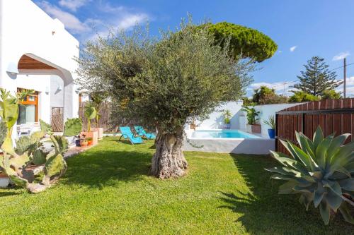 a tree in the yard of a house with a pool at La Ballena Azul CONIL in Cádiz