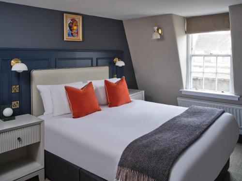 een slaapkamer met een groot wit bed met oranje kussens bij Henrietta House, a member of Radisson Individuals in Bath