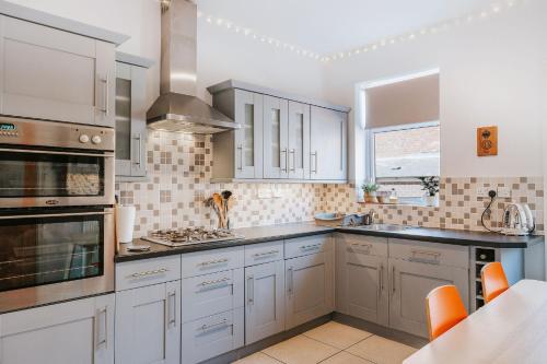 a kitchen with white cabinets and a stove top oven at 3 Bed - Modern Comfortable Stay - Preston City Centre in Preston