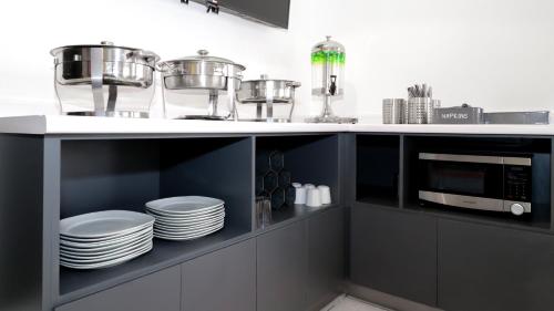 a kitchen with a counter with plates and a microwave at Hotel Casa Blanca Minero in Fresnillo de González Echeverría