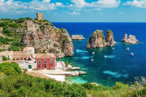 a red building in the water next to a mountain at Camera Tina in Castellammare del Golfo