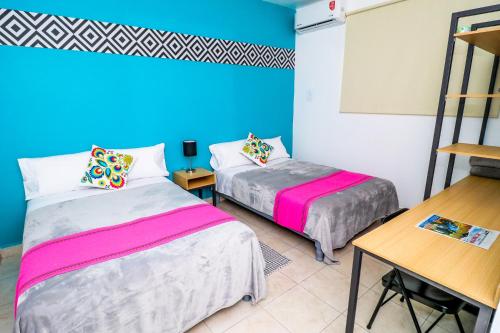 a room with two beds and a table and a desk at Hotel Casa Blanca Minero in Fresnillo de González Echeverría