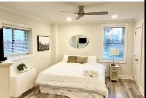 Cozy Downtown Atlanta Condo في أتلانتا: غرفة نوم بيضاء مع سرير ومروحة