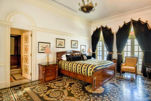 a bedroom with a bed and a chair and windows at The Villa Casa Casuarina in Miami Beach