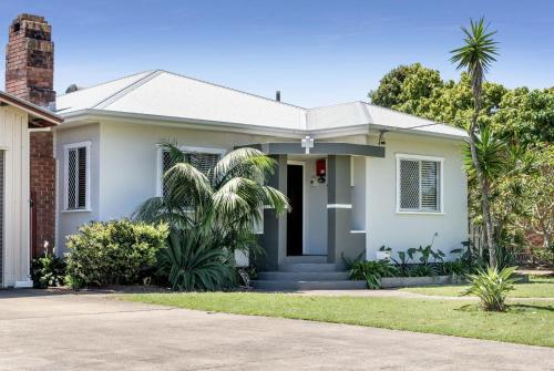 a white house with palm trees in front of it at Wattleseed - 4 Wattle Street in Evans Head