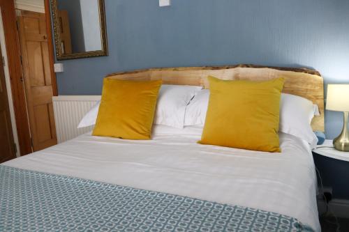 a bed with two yellow pillows on top of it at Arosfa Harbourside Aberaeron in Aberaeron