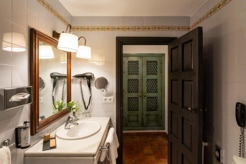 a bathroom with a sink and a mirror and a door at Parador de Almagro in Almagro