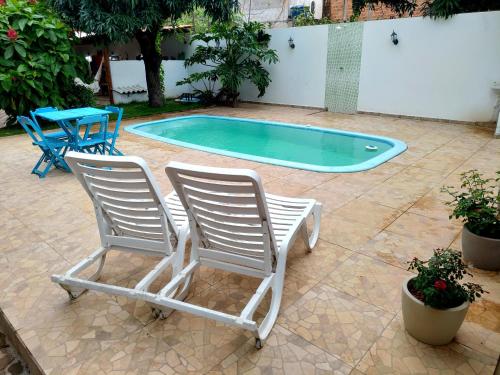 Duas cadeiras, uma mesa e uma piscina. em Pousada Caminhos da Chapada em Palmeiras