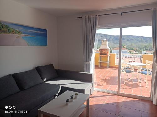 a living room with a couch and a view of a patio at ELE HAUSE Tropical Paradise in Tarajalejo