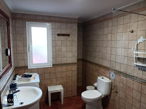 a bathroom with a toilet and a sink and a window at ELE HAUSE Tropical Paradise in Tarajalejo