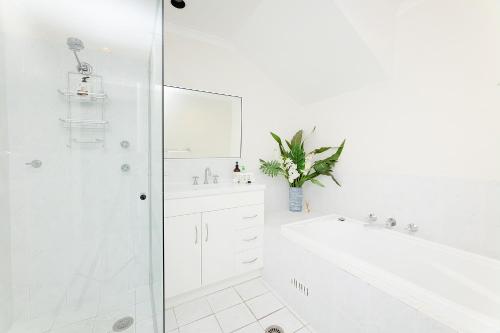 a white bathroom with a shower and a tub and a sink at Coral Sands 2 in Forster