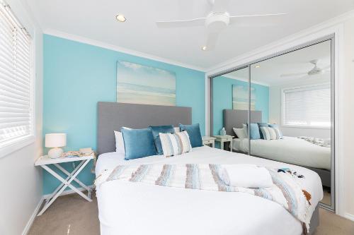 two beds in a room with blue walls at Coral Sands 2 in Forster