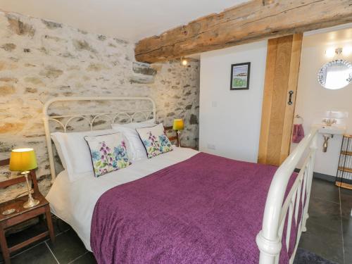 a bedroom with a white bed with purple sheets at Cwch Gwenyn in Holyhead