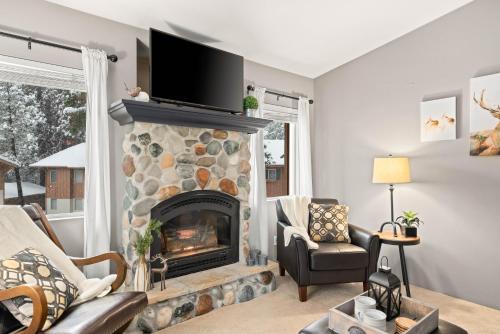 a living room with a stone fireplace with a tv above it at Walk to Downtown Festivities 2Bd2Ba Condo in Leavenworth