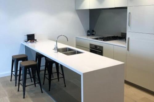 a kitchen with a white counter top and stools at Great Corporate One Bedroom ATC006911 in Sydney