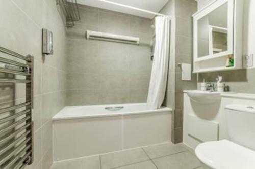 y baño con bañera, aseo y lavamanos. en Luxury 2 bedroom apartment in Central London with free Parking, en Londres